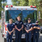 Firemen posing in front of Fire engine.