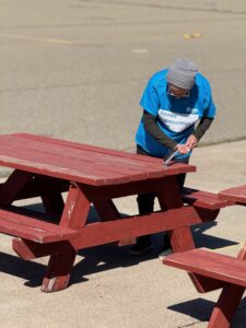 Volunteer helping to refinish the picnic tables.